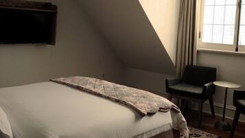 A bedroom with a large bed, a small table, and a chair.