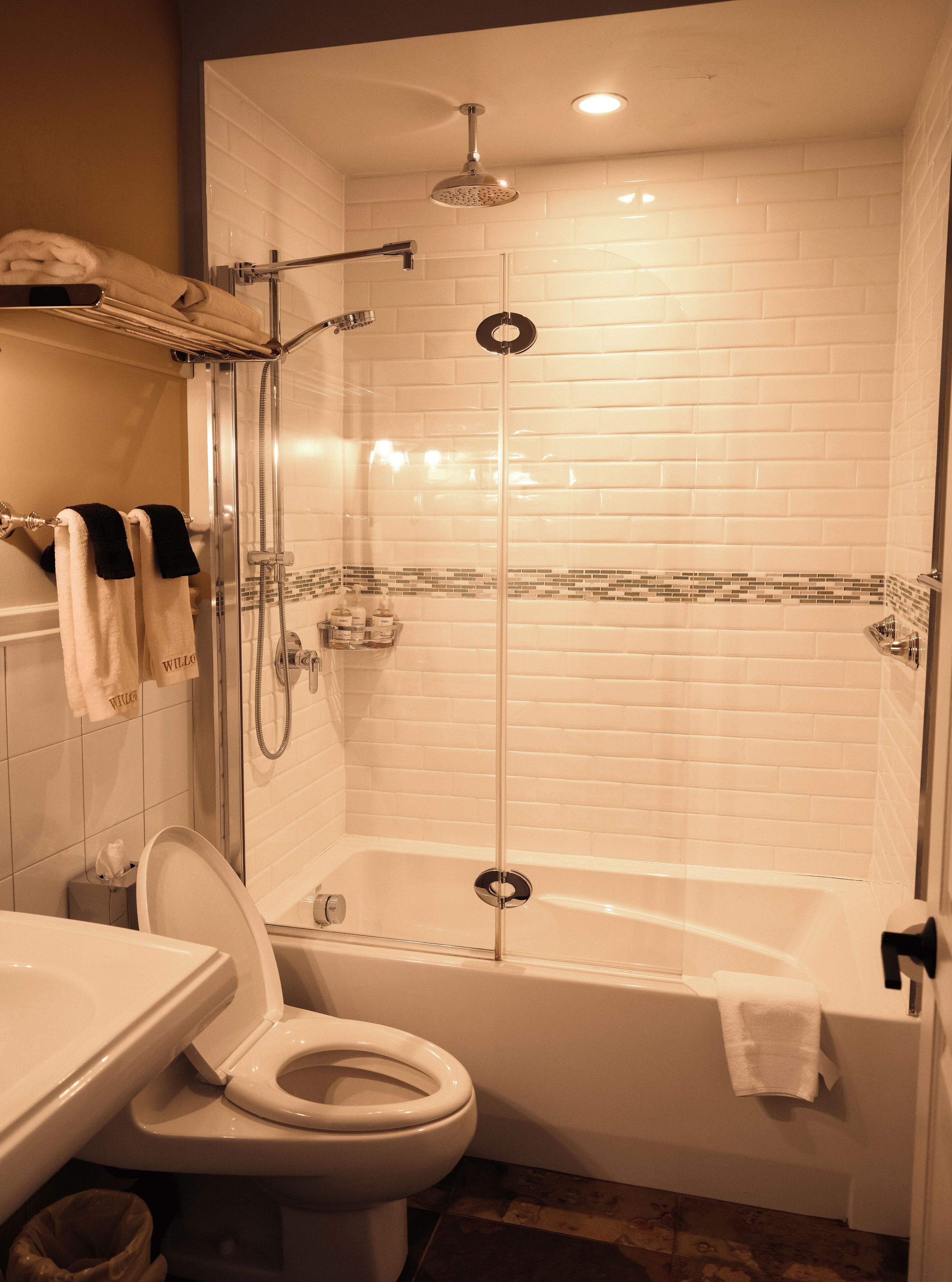 A bathroom with a glass-enclosed shower, a bathtub, and a toilet.