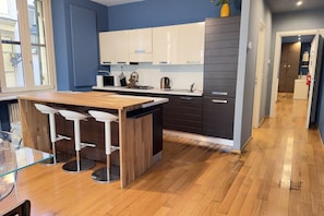 Een moderne keuken met een houten kookeiland en barkrukken, een blauwe accentmuur en uitzicht op de stad.