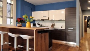 Cozinha moderna com área de bar, piso de madeira e vista para o aposento vizinho.