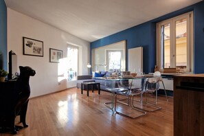 Een ruime woonkamer met een eethoek, een grote spiegel en een zwart hondenbeeld.