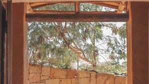 A stone wall with a wooden door and a view of trees outside. - Hotel Ambil (Barichara)