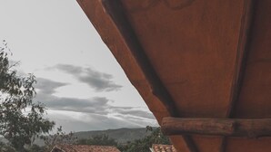 A wooden deck with two wooden chairs and a small round table. - Hotel Ambil (Barichara)