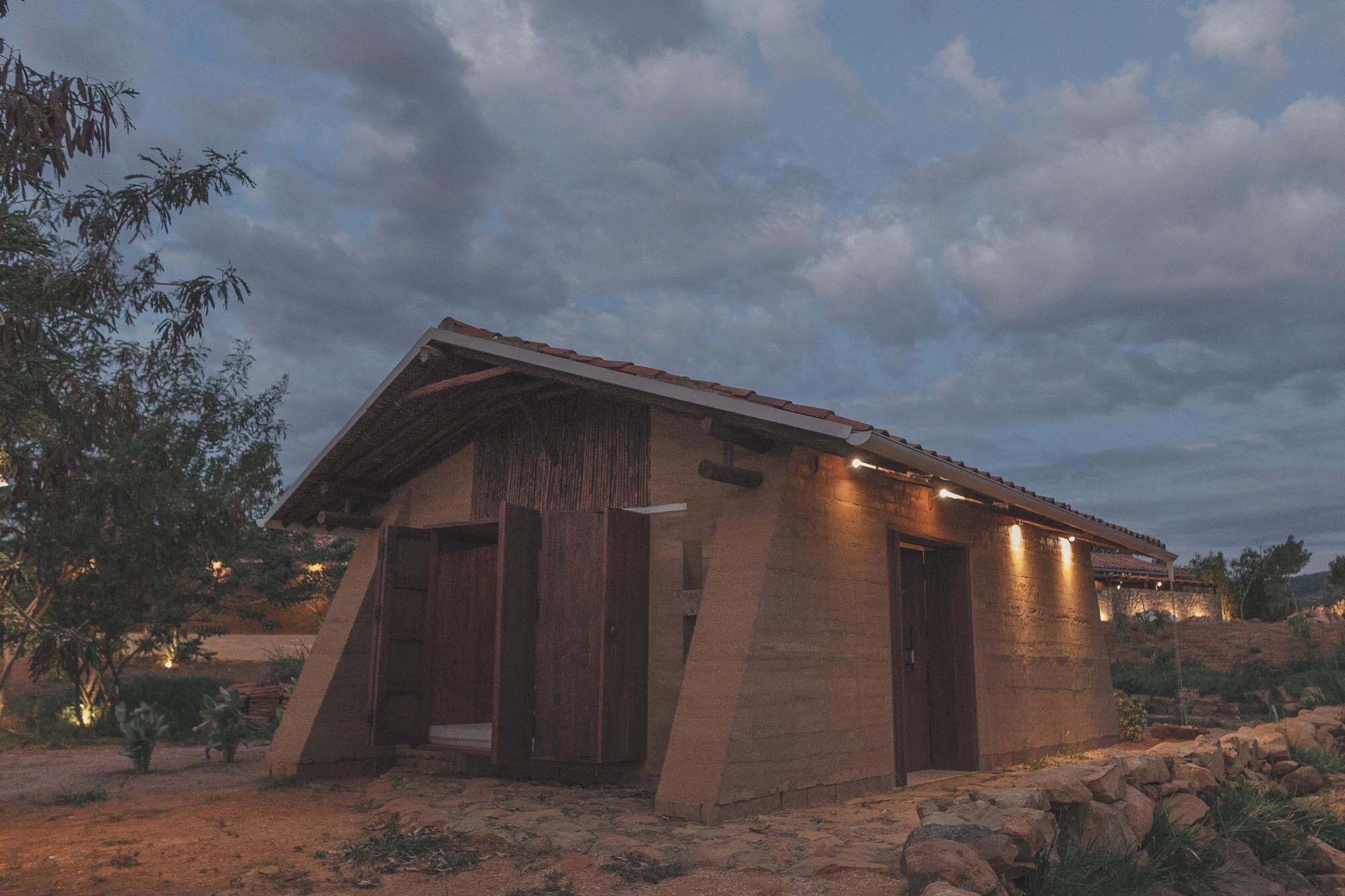 A rustic building with a sloped roof, wooden doors, and a well-lit exterior.