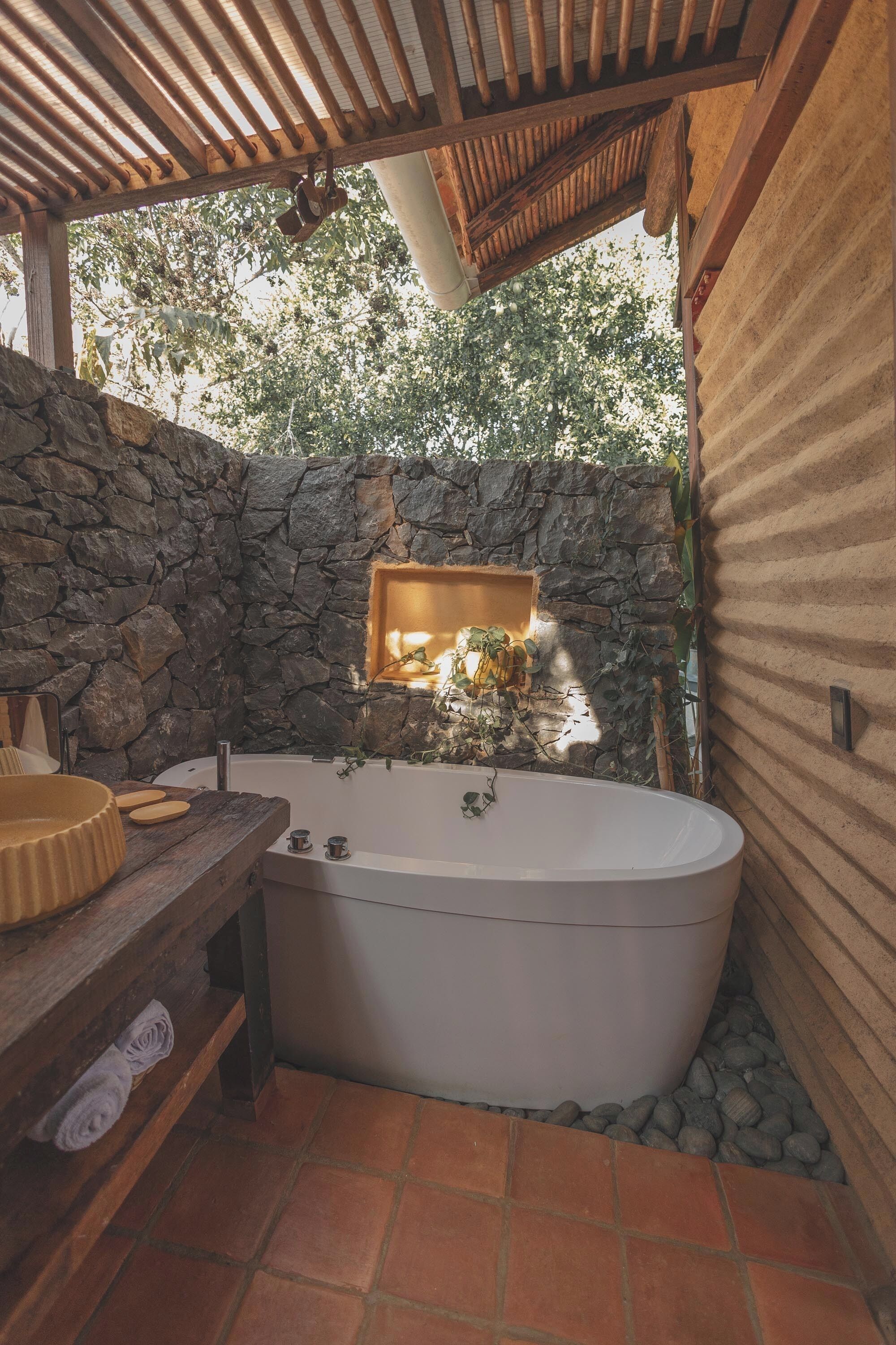 Une salle de bain avec une baignoire sur pieds, un meuble-lavabo en bois et un mur en pierre.