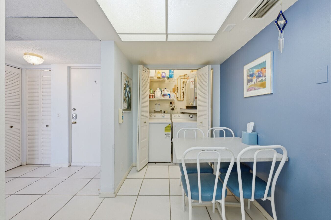 A compact kitchen with a dining table and chairs, a refrigerator, and a microwave.