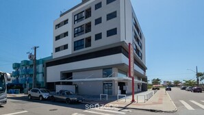 A multi-story building with a flat facade, large windows, and a visible entrance. - Fully Equipped apt Near the Beach Rcq0305 (Florianópolis)
