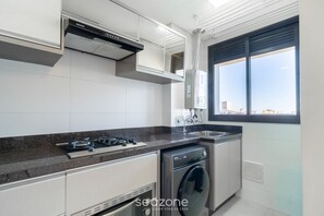Een moderne keuken met een gasfornuis, een ingebouwde oven en een wasmachine.