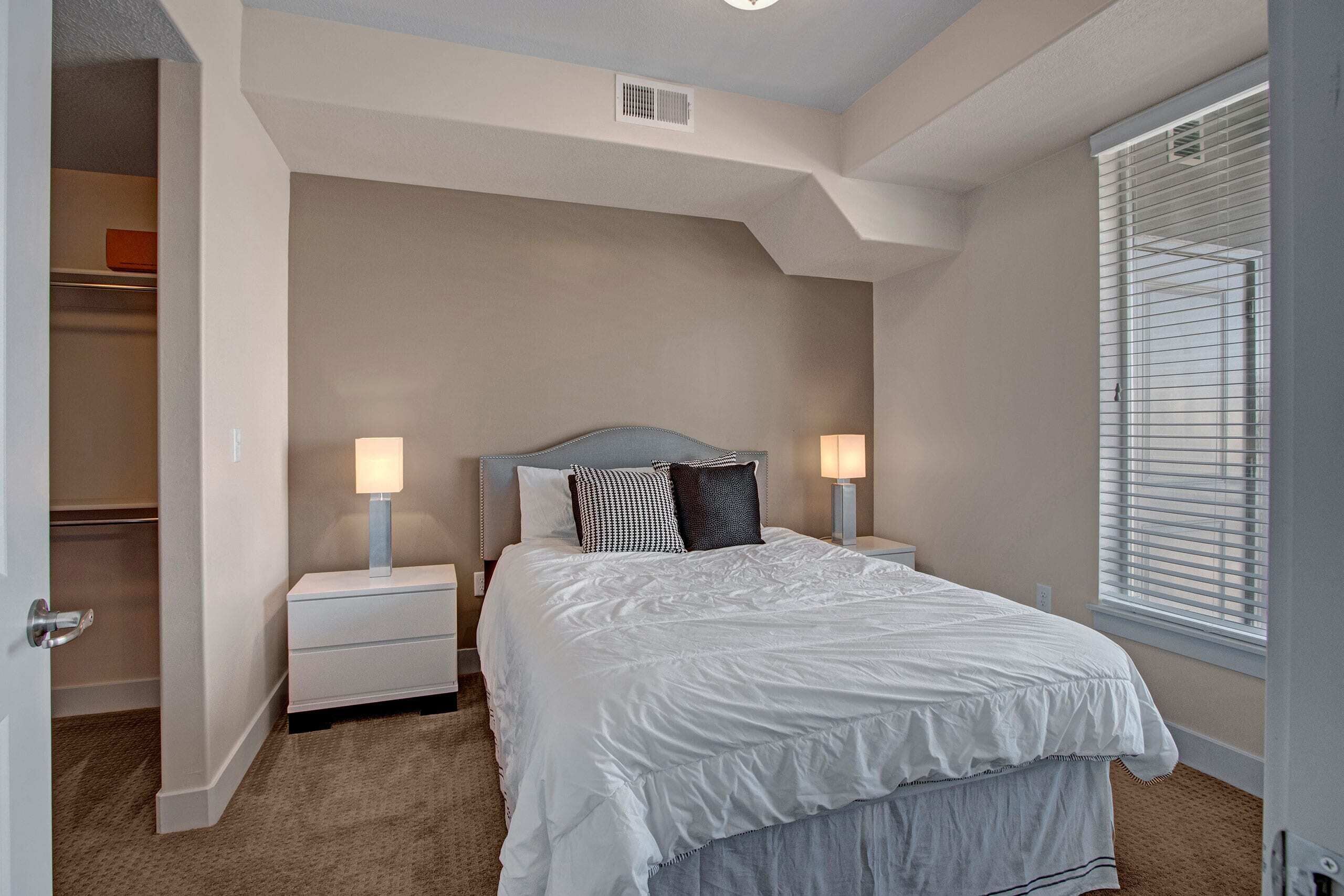 A bedroom with a bed, nightstands, and a window.