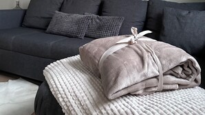 Ein modernes Wohnzimmer mit einem grauen Sofa, dekorativen Kissen und zwei an der Wand hängenden Bildern von Hirschen.