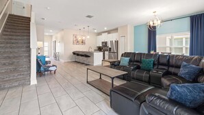 A spacious living room with a leather sofa, a coffee table, and a staircase. - Magical Retreat at Championsgate (Davenport)