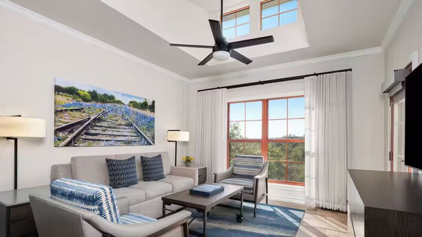 A modern hotel room with a large window, a ceiling fan, a sofa, a coffee table, and a TV. - Charming 1-bedroom villa with AC in fantastic San Antonio (San Antonio)