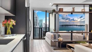 A modern kitchen with a black faucet, a vase of flowers, and a book titled "LAND IN SKY". - New Open Concept Studio | Walk to Bayfront Park (Miami)