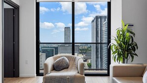 Un salon moderne avec une grande fenêtre, un canapé, un fauteuil et une plante en pot.