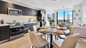 Une cuisine moderne équipée d’un four à micro-ondes, d’un four et d’une cuisinière intégrés. On y trouve un coin repas avec une table ronde et des chaises, ainsi qu’un canapé dans le salon.