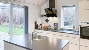 Een moderne keuken met een groot eiland, roestvrijstalen apparatuur en grote ramen met uitzicht op de omgeving.