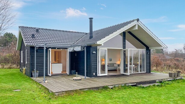 Een modern huis met een ruim terras, een schoorsteen en een schuifdeur die leidt naar een woonruimte.