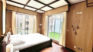 A modern bedroom with a large bed, wooden flooring, and a sliding glass door leading to a balcony. - Family Friendly 2BR Apartment • Terrace - Parking - Neuilly-sur-Seine/La Defense (Neuilly-sur-Seine)