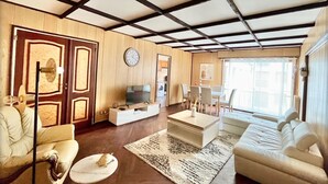 A living room with a TV, sofa, chairs, and a clock on the wall. - Family Friendly 2BR Apartment • Terrace - Parking - Neuilly-sur-Seine/La Defense (Neuilly-sur-Seine)