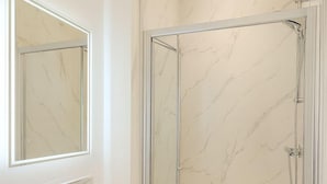 A bathroom with a white sink, a mirror, and a glass-enclosed shower. - The Miles Arms Hotel (Bristol)