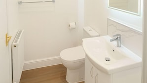 A small, white bathroom with a toilet, a sink, and a mirror. - The Miles Arms Hotel (Bristol)