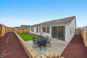 Een modern huis met een terras, een gazon en een houten omheining.