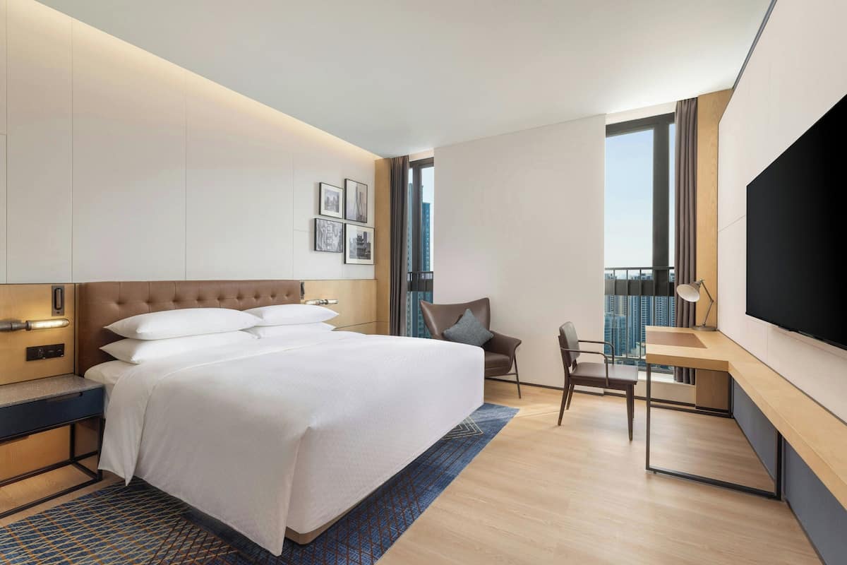 Una habitación de hotel moderna con una cama grande, un escritorio y un televisor.
