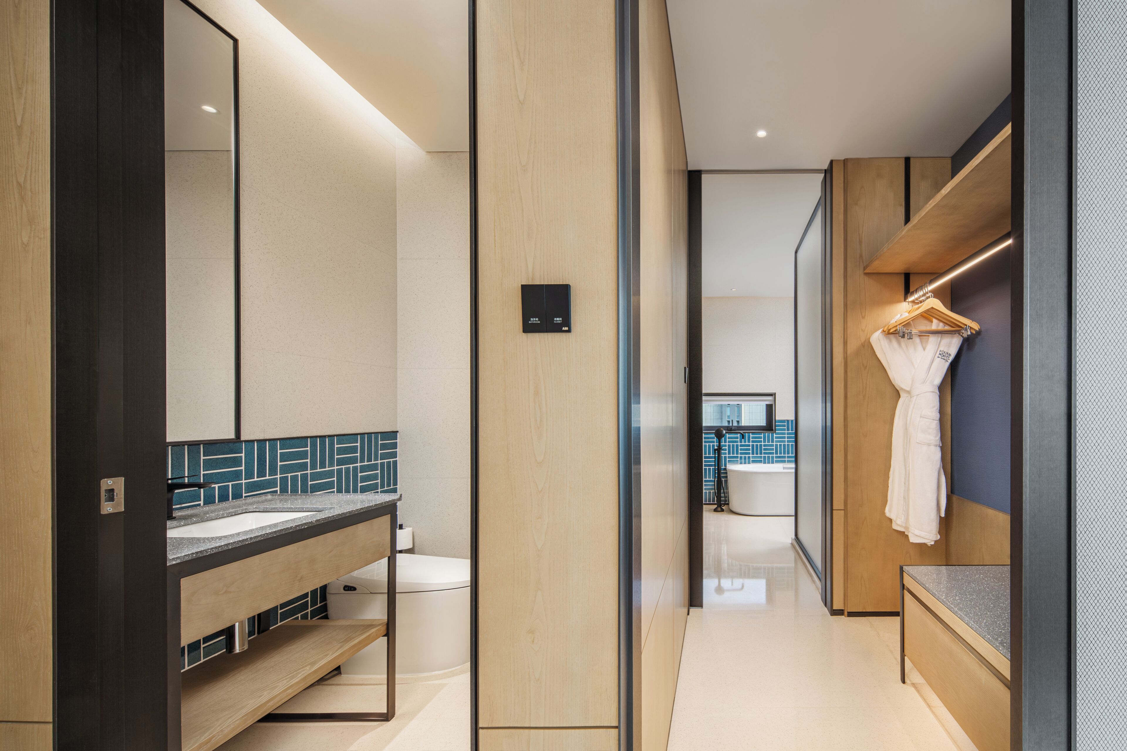 A modern bathroom with a wooden vanity, a mirror, and a towel rack.