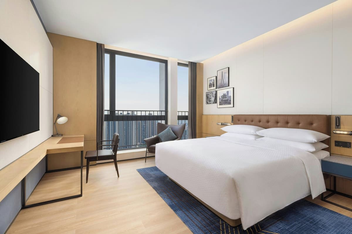 Una habitación de hotel moderna con una cama grande, un escritorio, una silla y un televisor.