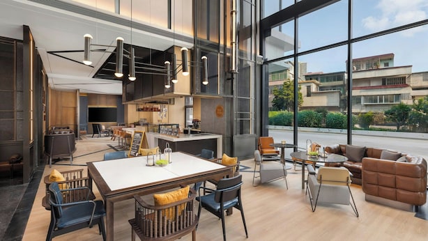 A modern hotel lobby with a dining area, seating arrangements, and large windows offering a view of the cityscape. - Four Points By Sheraton Guangzhou Bai’E Tan (Guangzhou)