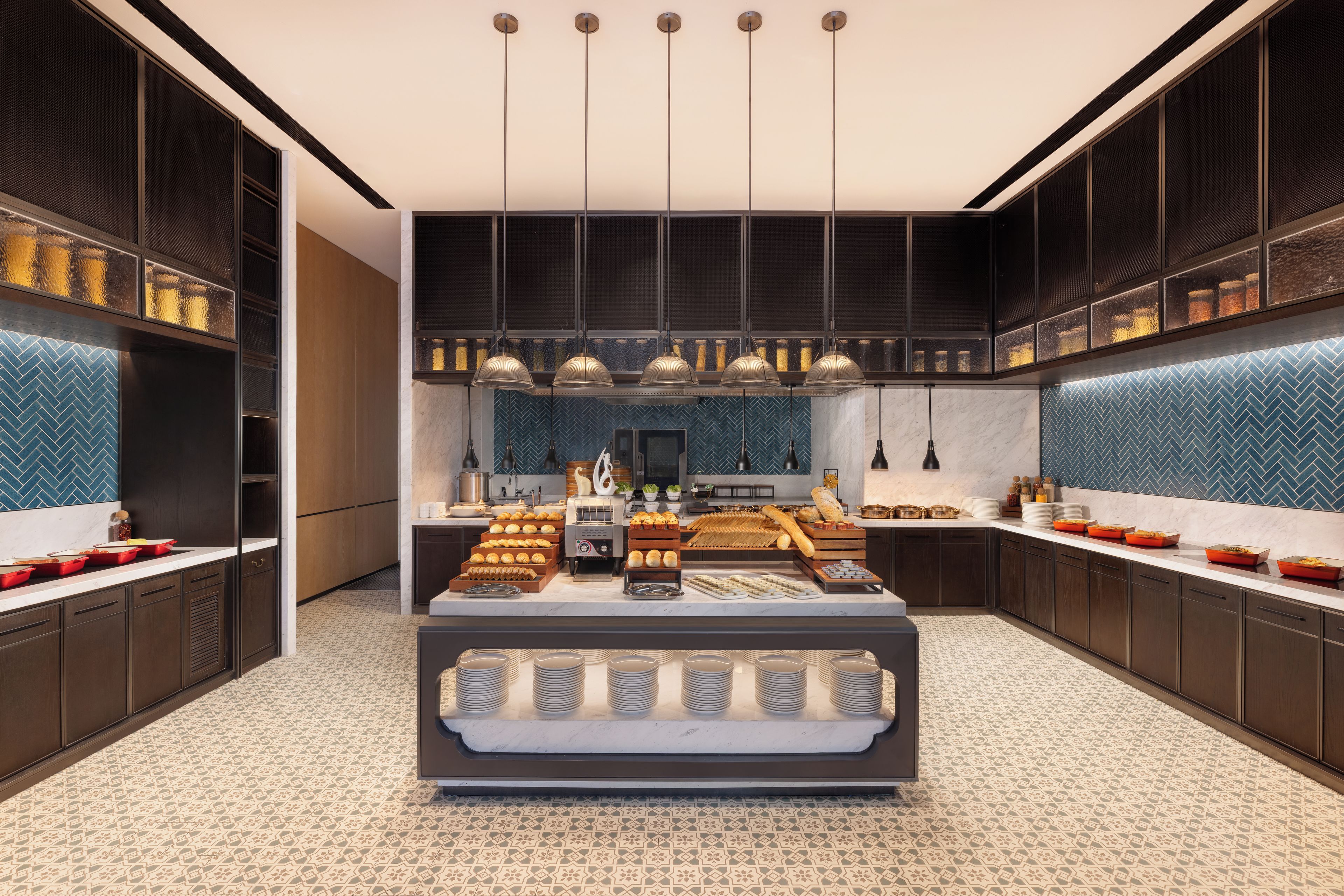 Una cocina moderna con una isla central, iluminación colgante y un salpicadero con diseño.