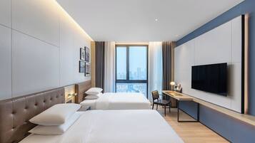 Habitación de hotel con dos camas, un escritorio, una silla, televisión de pantalla plana y vistas a la ciudad.
