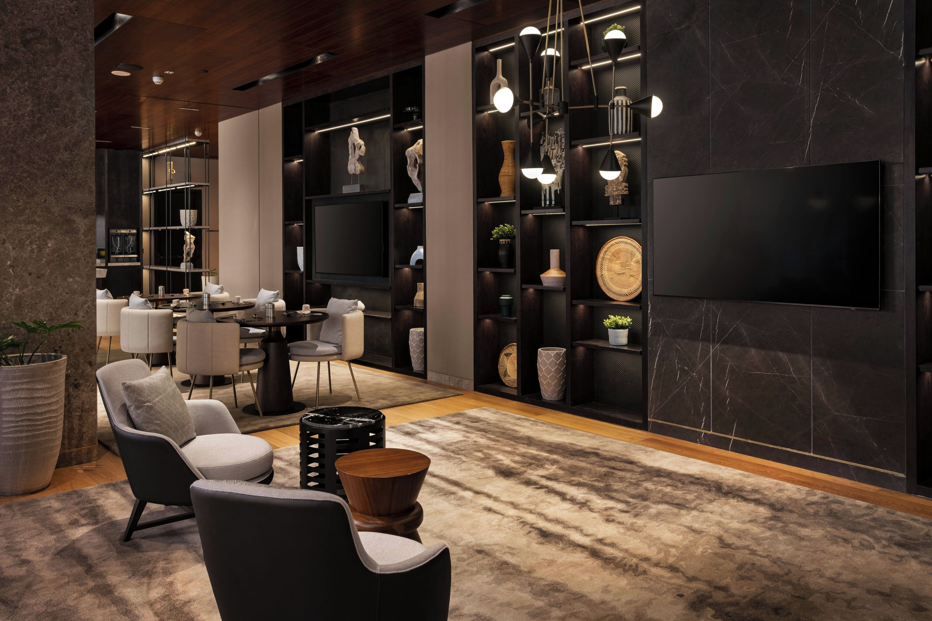 A modern living room with a flat-screen TV, comfortable seating, and a decorative wall with shelves.