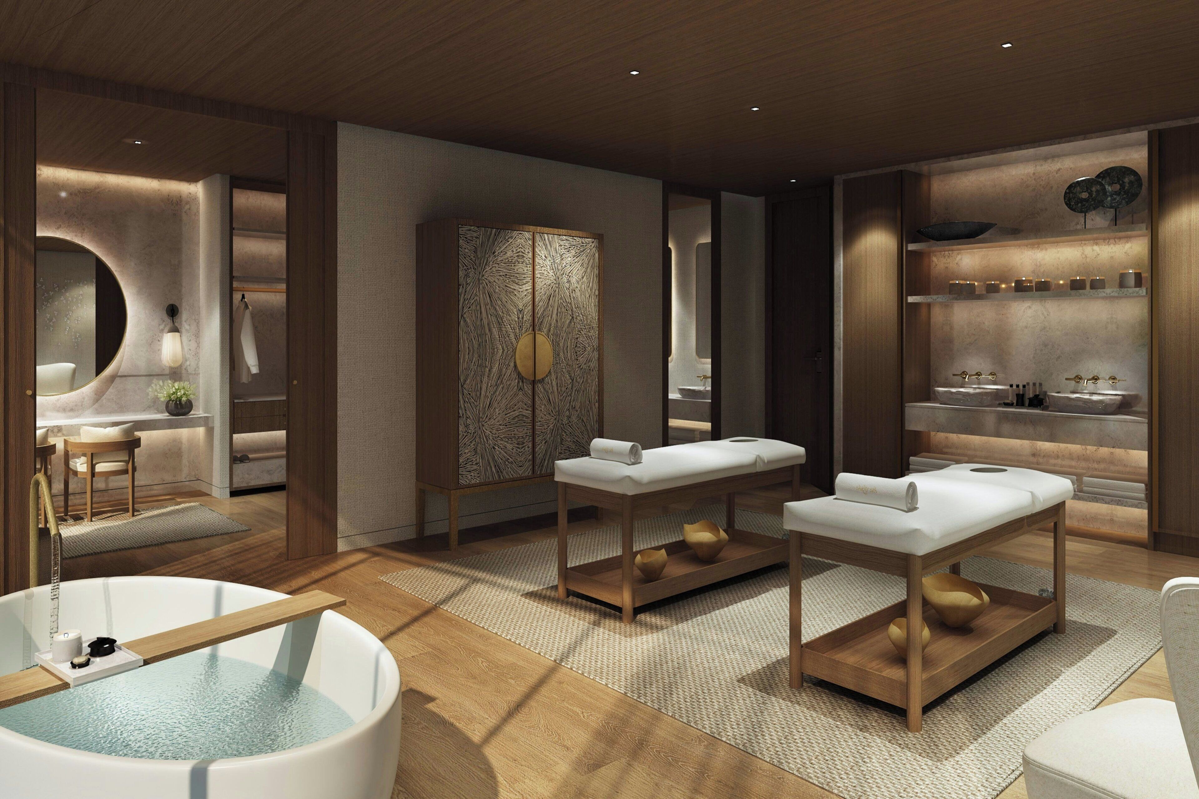 Un moderno spa con una bañera grande, dos camillas de masaje, un armario de madera y un estante con artículos de aseo.