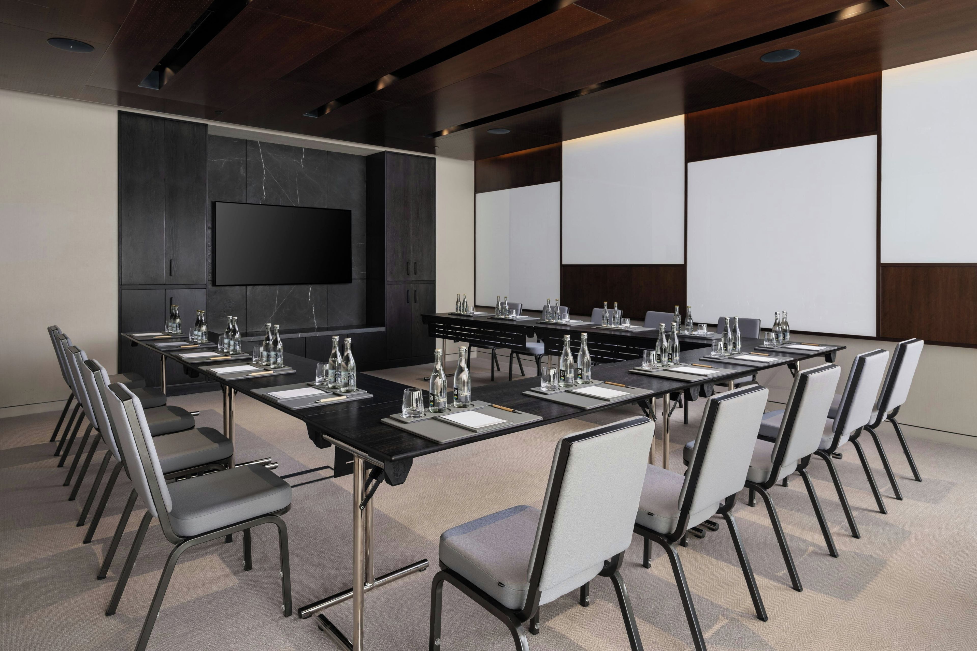 A conference room with a long table, chairs, a flat-screen TV, and a whiteboard.