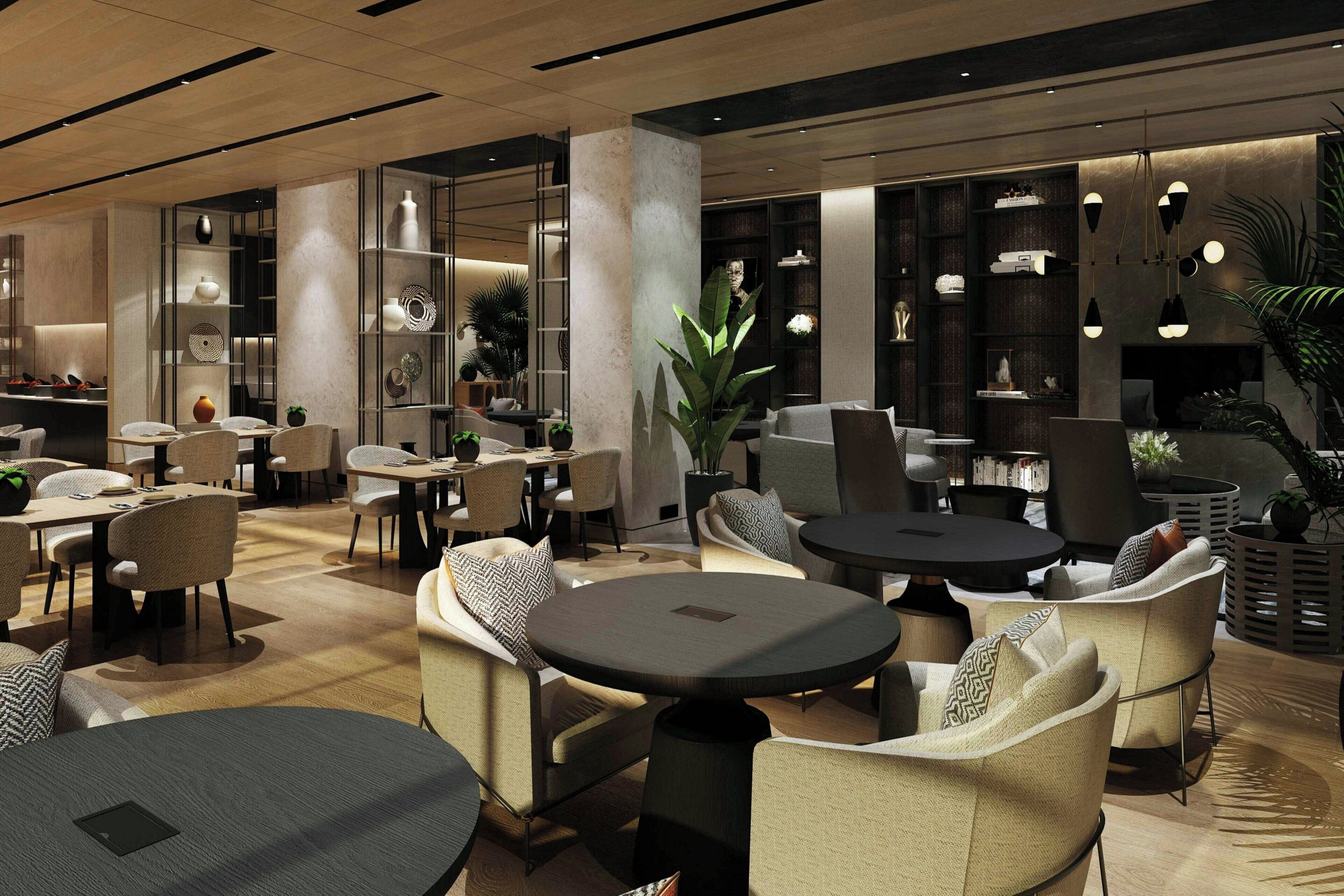 Una hall d'albergo moderna con tavoli rotondi, sedute confortevoli ed eleganti scaffali decorativi.