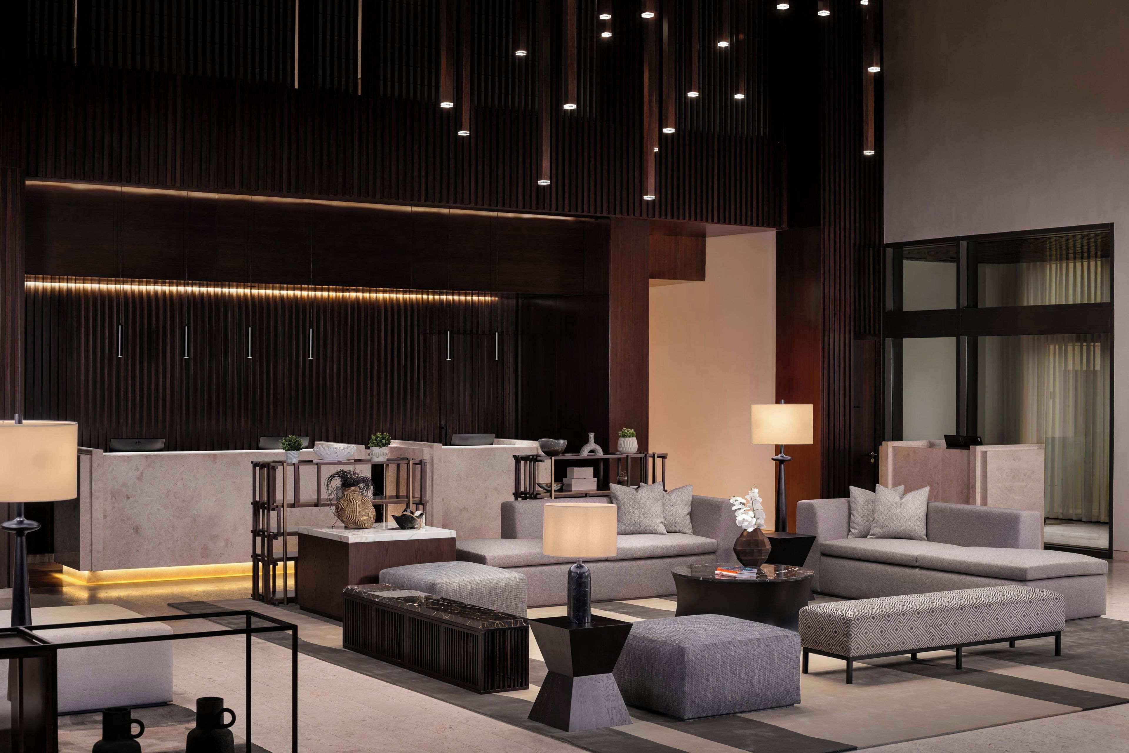 A modern lobby with a seating area, a reception desk, and a large window.
