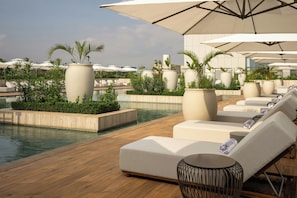 A rooftop pool area with lounge chairs, umbrellas, and potted plants. - Kampala Marriott Hotel (Kampala)