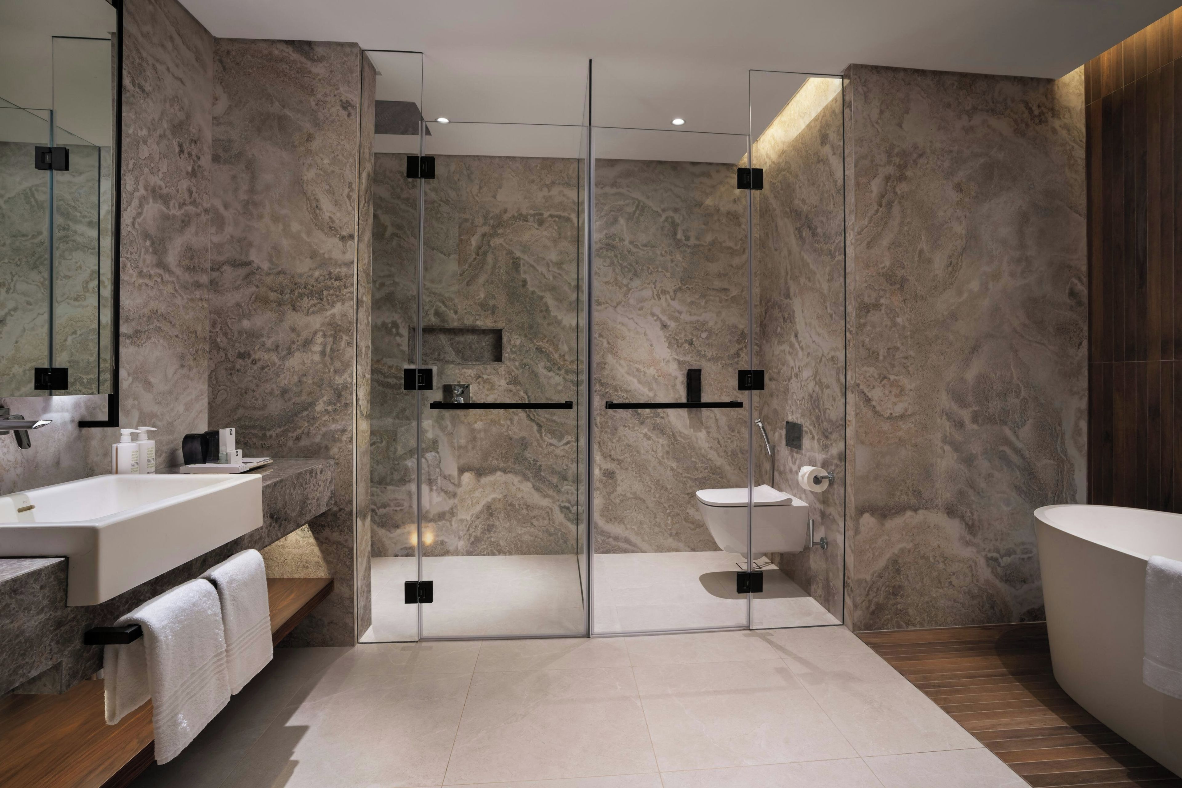 A modern bathroom with a glass-enclosed shower, a white sink, and a freestanding bathtub.