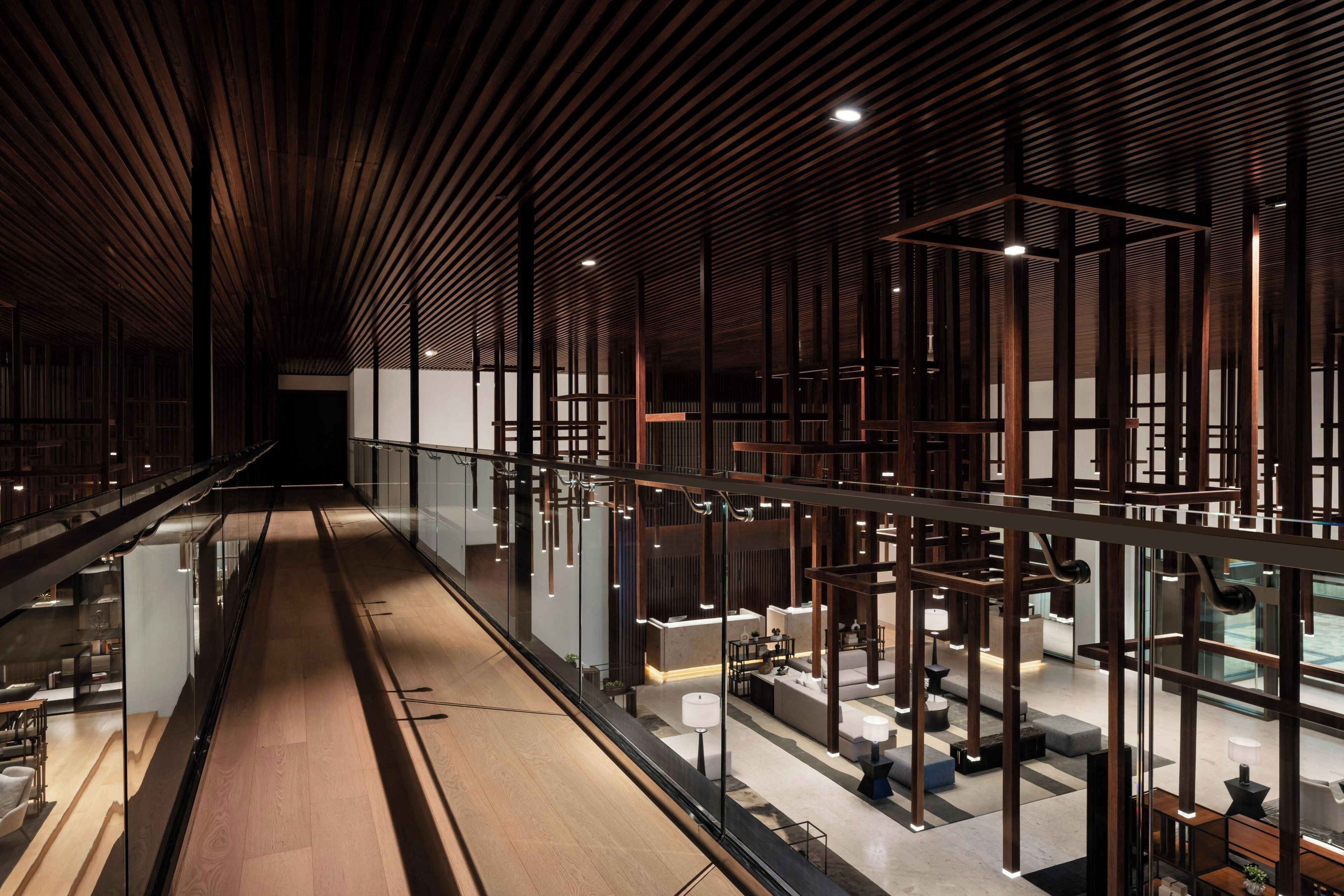 A modern interior with a long corridor, glass partitions, and wooden paneling.