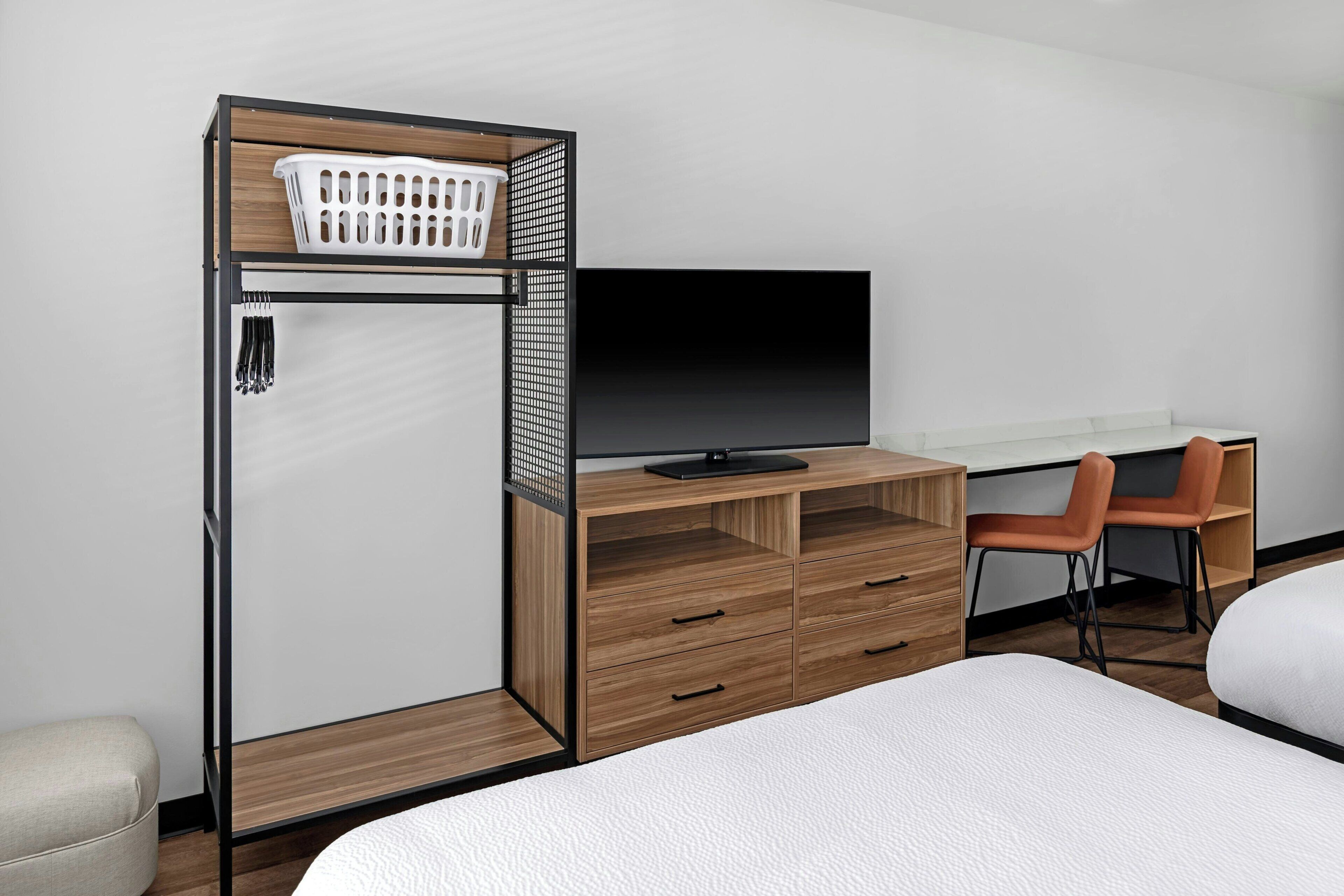 A bedroom with a bed, a desk with a TV, a chair, and a wardrobe.