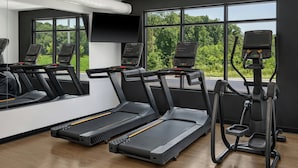 Une salle de sport équipée de tapis de course, d’un vélo d’appartement et d’un rameur.