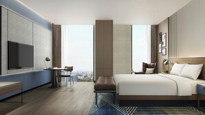 Una habitación de hotel moderna con una cama grande, un escritorio, una silla y un televisor.