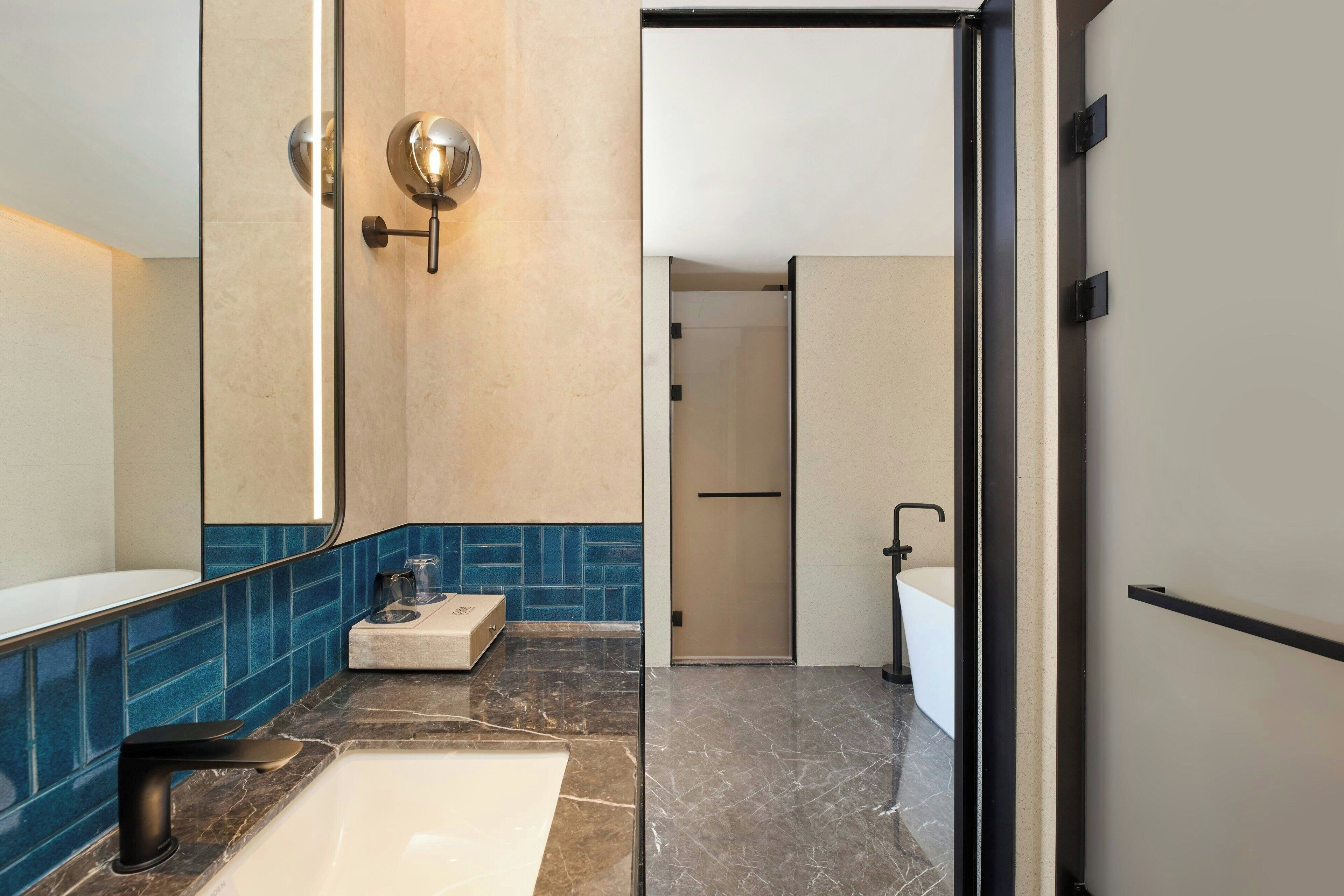 A modern bathroom with a large mirror, a white sink, and a shower area.