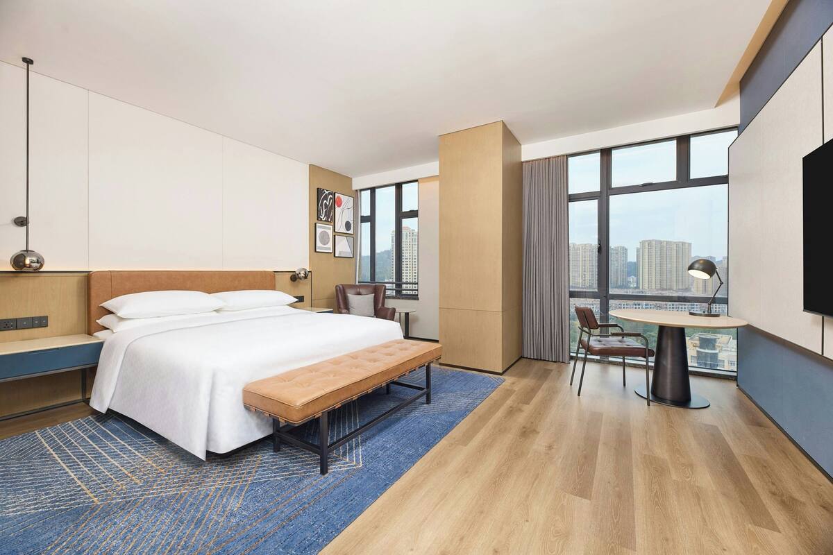 Una habitación de hotel moderna con una cama grande, un escritorio y vistas a la ciudad.