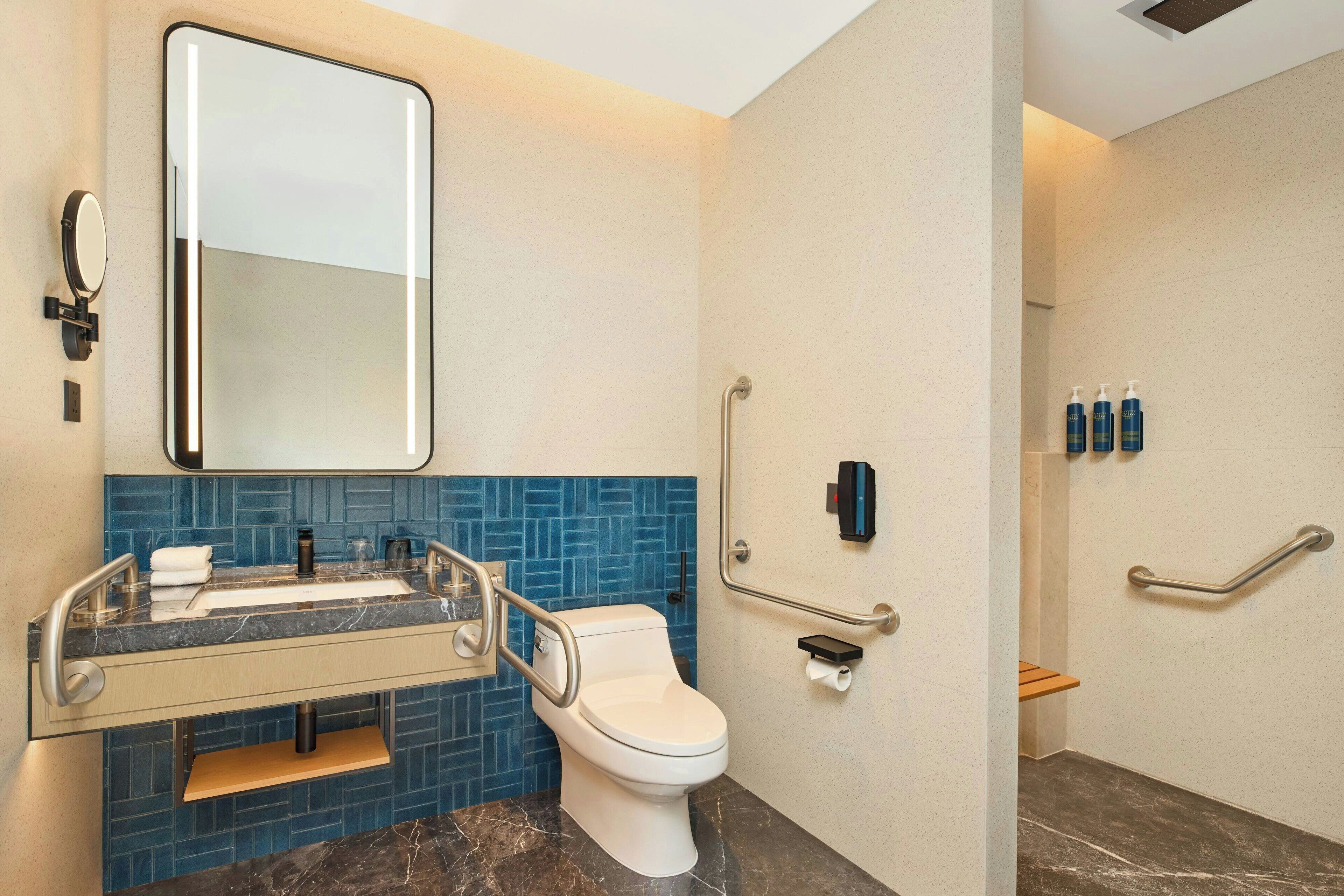 A modern bathroom with a white toilet, a sink with a mirror, and blue-tiled walls.