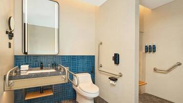 A modern bathroom with a white toilet, a sink with a mirror, and blue-tiled walls.