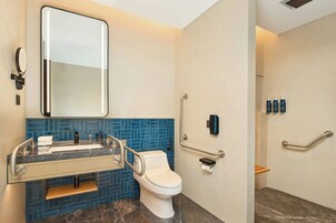 A modern bathroom with a white toilet, a sink with a mirror, and blue-tiled walls.