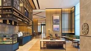 Un moderno vestíbulo de hotel con zona de bar, espacios de descanso y obras de arte en las paredes.