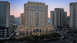 Un hotel de gran altura con un diseño arquitectónico clásico, que presenta ventanas arqueadas y una señalización destacada en la parte superior.